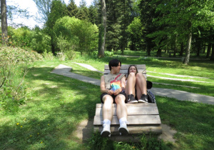 Dwójka uczniów odpoczywa na ławeczce w parku